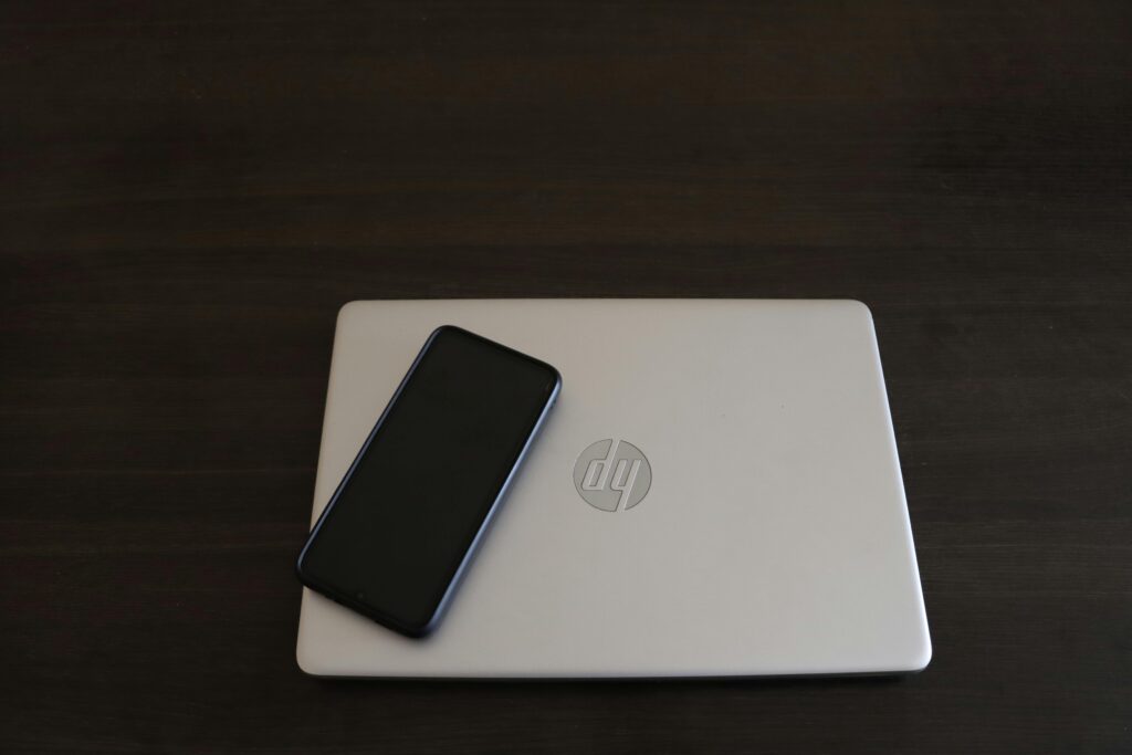 Close-up of a smartphone resting on an HP laptop, symbolizing modern technology integration.