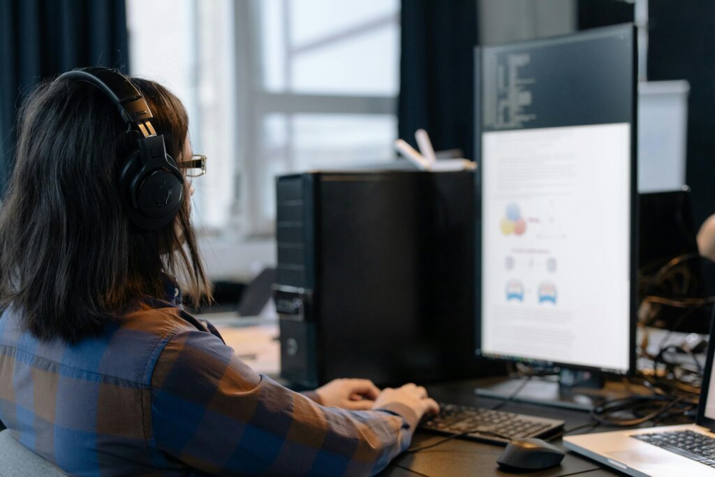 IT professional working on a computer in a modern office setting, focused on coding and tasks.