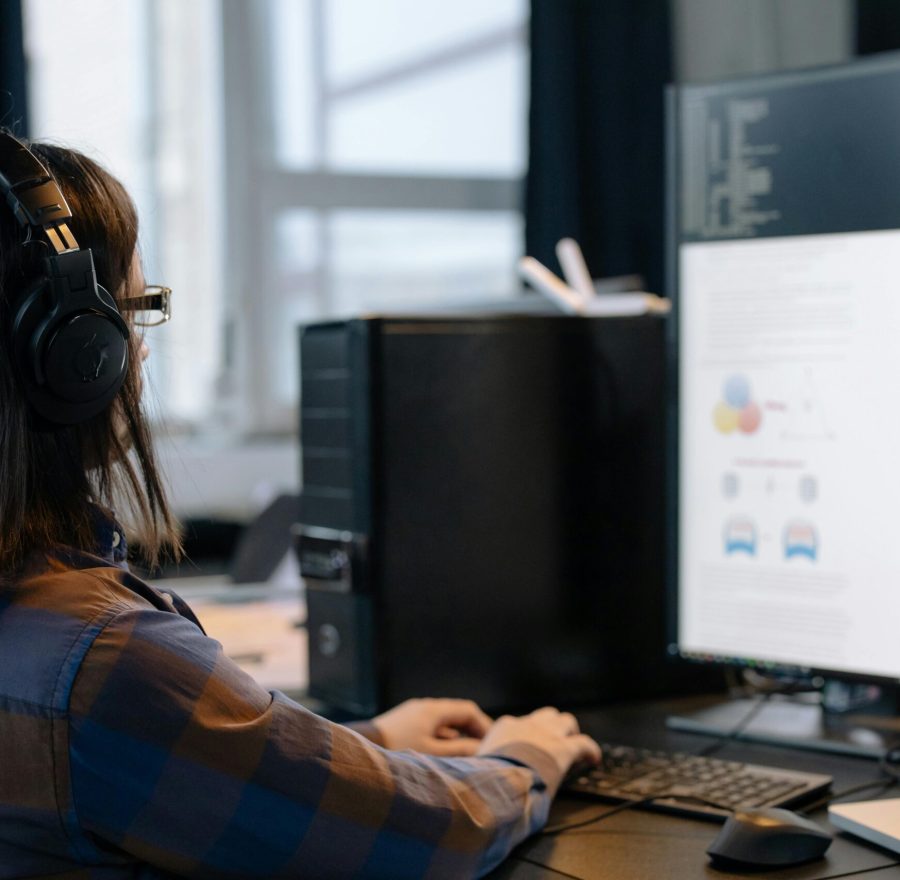 IT professional working on a computer in a modern office setting, focused on coding and tasks.